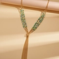 Dettaglio della collana boho a tre strati con perline verdi e nappe in metallo dorato - Verde
