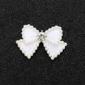 Detailed view of pearl bow charm with central rhinestone on a black glitter surface - Silver Base White Bow