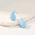 Macro shot of light blue teardrop earrings on a white textured stone surface - Light Blue
