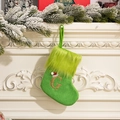 Green knit Christmas stocking featuring a fuzzy cuff and gold glitter letter G on a mantle - Letter G