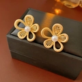Dettaglio di orecchini a fiore dorati con perle bianche su una scatola per gioielli nera - Oro