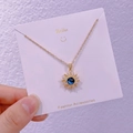 Dettaglio di una collana a girasole dorata con pietra blu stellata su espositore - Girasole Stellato (XK0033)