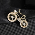Elegante broche de bicicleta dorado con cristales y perla blanca sobre tela negra - Bicicleta Dorada
