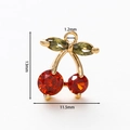 Macro view of 18k gold plated cherry pendant with red and green cubic zirconia detail - Cherry Pendant