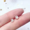 Minimalist 925 sterling silver flower stud earrings displayed on a fingertip - Sakura / Silver