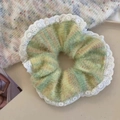 Detail of green plush scrunchie with white lace edges on a minimalist beige surface - Lace Rainbow Yellow