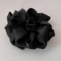 Detailaufnahme einer schwarzen Haarklammer aus Satin in Blumenform auf grauem Grund - Schwarz