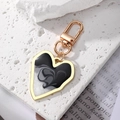Detailed close-up of heart keychain with marble texture and golden alloy clasp - Black & White