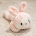 Plush bunny stuffed animal toy in pink and white soft fur laying on a textured rug - Pink Rabbit