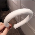 White plush candy color headband held by hand showcasing soft fuzzy texture - White