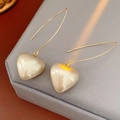 Close-up of vintage golden heart pearl drop earrings on a grey velvet jewelry box - White