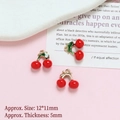 Detailed view of cherry-shaped gold-plated pendants for DIY jewelry crafting on pink surface - Cherry
