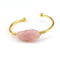 Close-up of rose quartz hexagon stone secured by hand-wrapped golden wire on cuff - Rose Quartz
