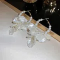 Gros plan de créoles dorées avec perles et pétales blancs irisés sur une surface dorée - Coquille de perle blanche dorée (21#)