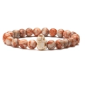 Detail of beaded stretch bracelet with brown stone beads and a white marble elephant charm - Red Network Stone