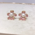 Gros plan de boucles d'oreilles fleur or 18K avec pétales roses, perle et cristaux - Rose Dégradé