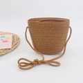 Close-up of a solid color children's woven straw bag with zipper and shoulder strap - Coffee