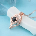 Macro detail of rose gold heart projection necklace with small diamonds on a blue background - Double Layer Asymmetric Heart Rose Gold