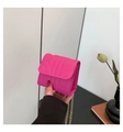 Magenta quilted mini crossbody bag with gold chain strap held against a neutral interior - Rose Red