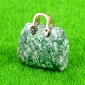 Miniature green spotted stone handbag pendant with gold metal handle on grass - Qinghai Jade