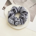 Elegant grey satin scrunchie with silky texture placed on a cream ceramic coaster - Smoke