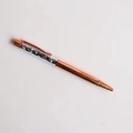 Macro shot of a rose gold crystal ballpoint pen filled with black gravel stones inside - Terahertz
