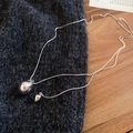 Vue macro des pendentifs goutte sur pull gris en maille avec finition argent polie - Argenté