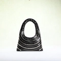 Close-up of silver studs on black leather bag showcasing punk style metal hardware - Black