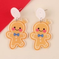 Close-up of cute gingerbread man earrings with blue bow and sparkling glitter finish - Crown Smiling Gingerbread Man