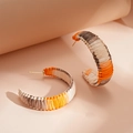Macro shot of colorful woven C-shaped hoop earrings with vibrant raffia texture - Yellow