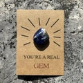 Macro detail of natural sodalite stone on a brown kraft card with 'YOU'RE A REAL GEM' text - Blue Sodalite