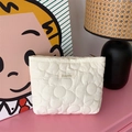 Detailed view of a cute white quilted floral pattern cosmetic bag on a stylish pink desk - White