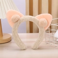 Dettaglio di un cerchietto in peluche beige con orecchie di gatto rosa e morbidi pompon - Beige e Rosa