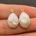 Natural white baroque pearl pendants with golden metal loops held between fingers - No.4 (12x19mm)