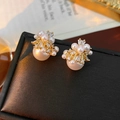 Detail van vintage gouden oorbellen met witte parels en sprankelende zirkonia stenen - Goud