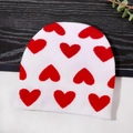 Berretto in maglia bianca con cuori rossi su sfondo in legno scuro e bianco - Taglia unica / Bianco