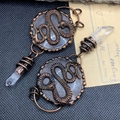 Macro detail of vintage bronze earrings with snake design and faceted crystal drop pendant - White Crystal Snake
