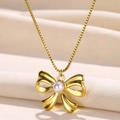 Elegant gold bow necklace with white pearl pendant on a soft white silk background - N06939g