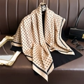 Pañuelo de seda con lunares en beige y negro, presentado colgado con un atuendo elegante - Caqui