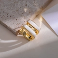 Details von goldenen quadratischen Creolen mit weißer Emaille auf strukturiertem Stein - Weiß