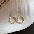Detailed view of polished gold hoop earrings on textured white fabric background - 20mm / Gold