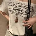 Detail of vintage brown leather bean pendant on long silver chain worn on a white tee - Silver Coffee Metal Style