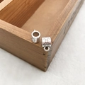 Vue macro de deux perles à fleurs évidées en argent vintage sur un plateau bois - 1 connecteur 3 voies 8x11mm Design C