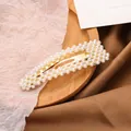 Elegante horquilla dorada con cuatro filas de perlas blancas en bandeja de madera - Dorado
