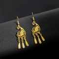 Close-up of golden ethnic peacock earrings with bell tassels and hollow floral design - E5765-1 Paisley Pattern Triple Dangle