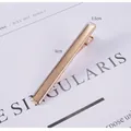 Minimalistische gouden 6cm haarklem met matte metaaltextuur gepresenteerd op tijdschrift - Nr. 2 Accessoire haarspeld