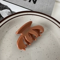 Close-up of caramel glossy claw clip with engraved text on minimalist ceramic plate - Cellulose Acetate Pumpkin Clip / Orange