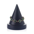 Golden chain bracelet featuring green heart-shaped gemstones on a black jewelry stand - Black