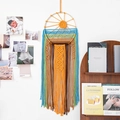 Handwoven sun-shaped macrame wall hanging with colorful tassels and a wooden frame - Sun