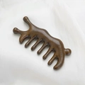 Macro shot of polished sandalwood meridian massage comb with five smooth teeth on white silk - Golden Sandalwood Ant Shape Massage Comb (11.5*5.2*2cm)